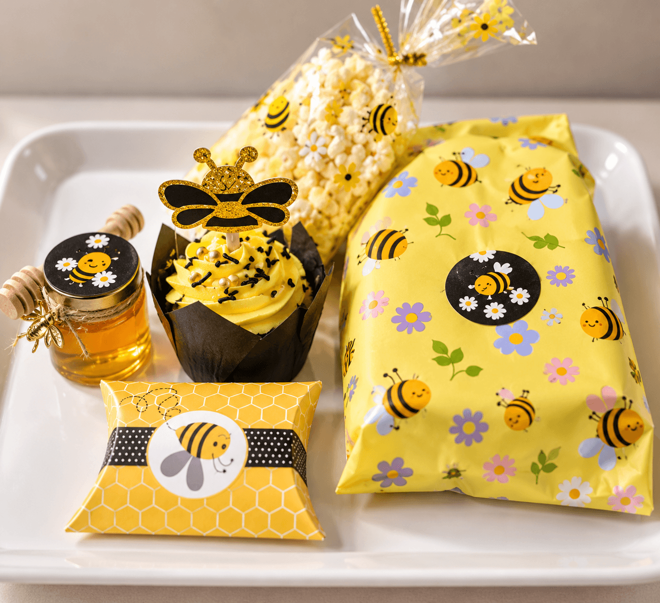 Bee-themed party favours: honey jar, cupcake, popcorn and gift box