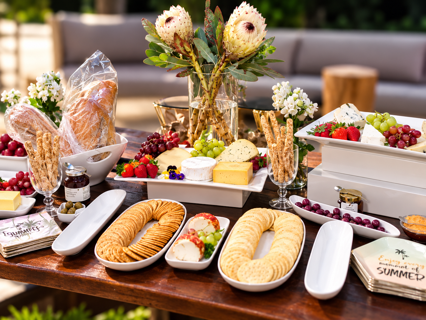Summer cheese table with crackers, grapes, strawberries, breadsticks and a protea centrepiece